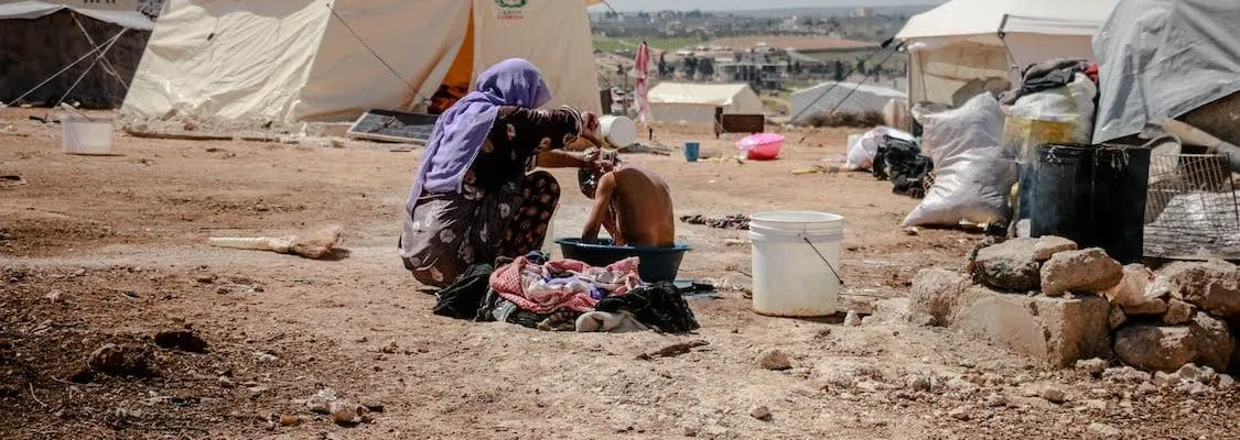 people sitting outside tent in refugee camp