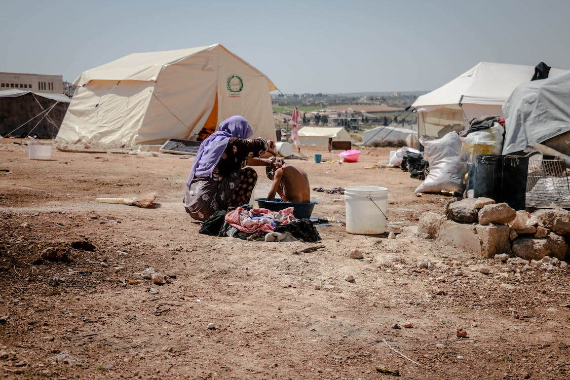 people sitting outside tent in refugee camp