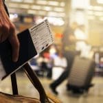 someone holding a boarding pass, passport, and travelling bag