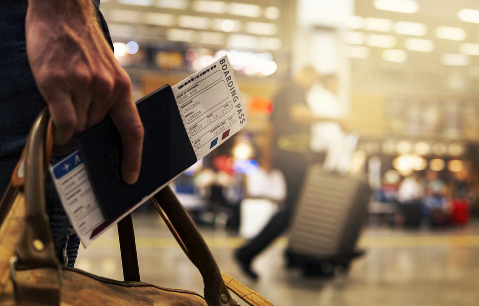 someone holding a boarding pass, passport, and travelling bag