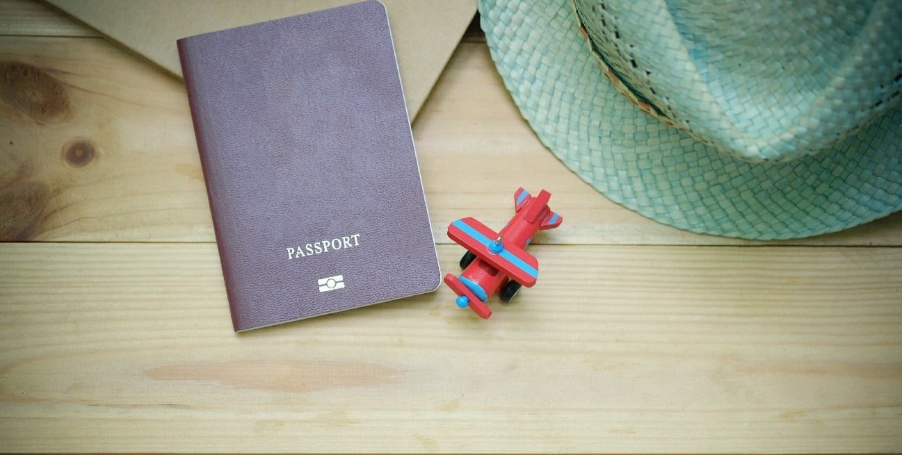 Passport on table, with toy plane and hat