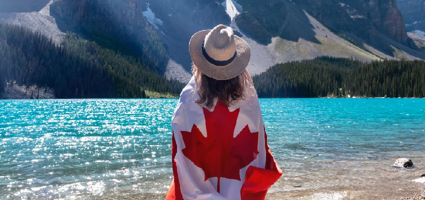 Woman wrapped in Canadian flag by the lake.