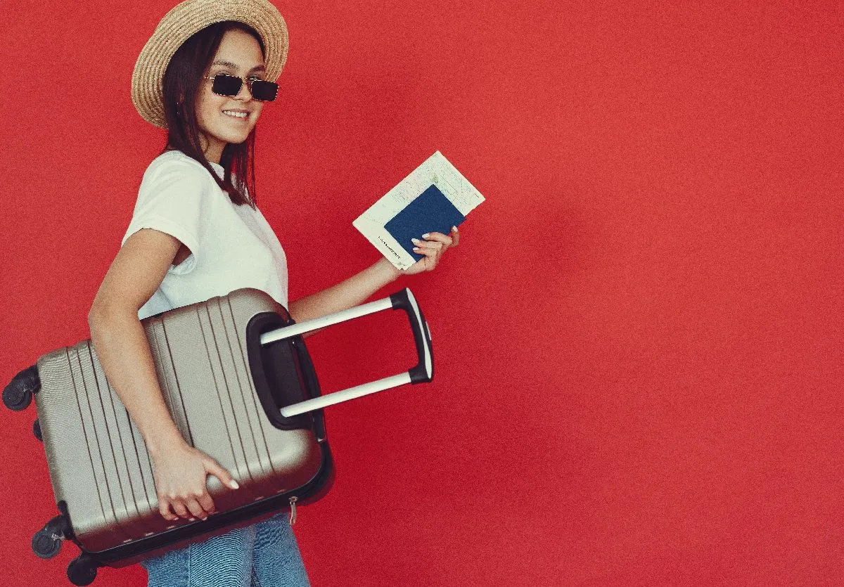 Young adult with passport and suitcase.