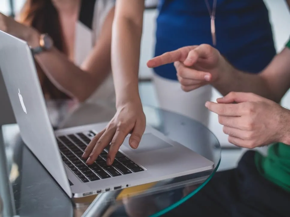 people gathered around a looking at a laptop.