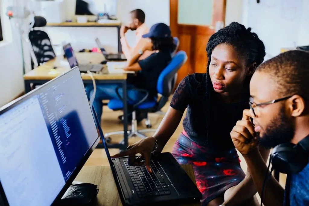 Two people sitting and looking at a computer screen.