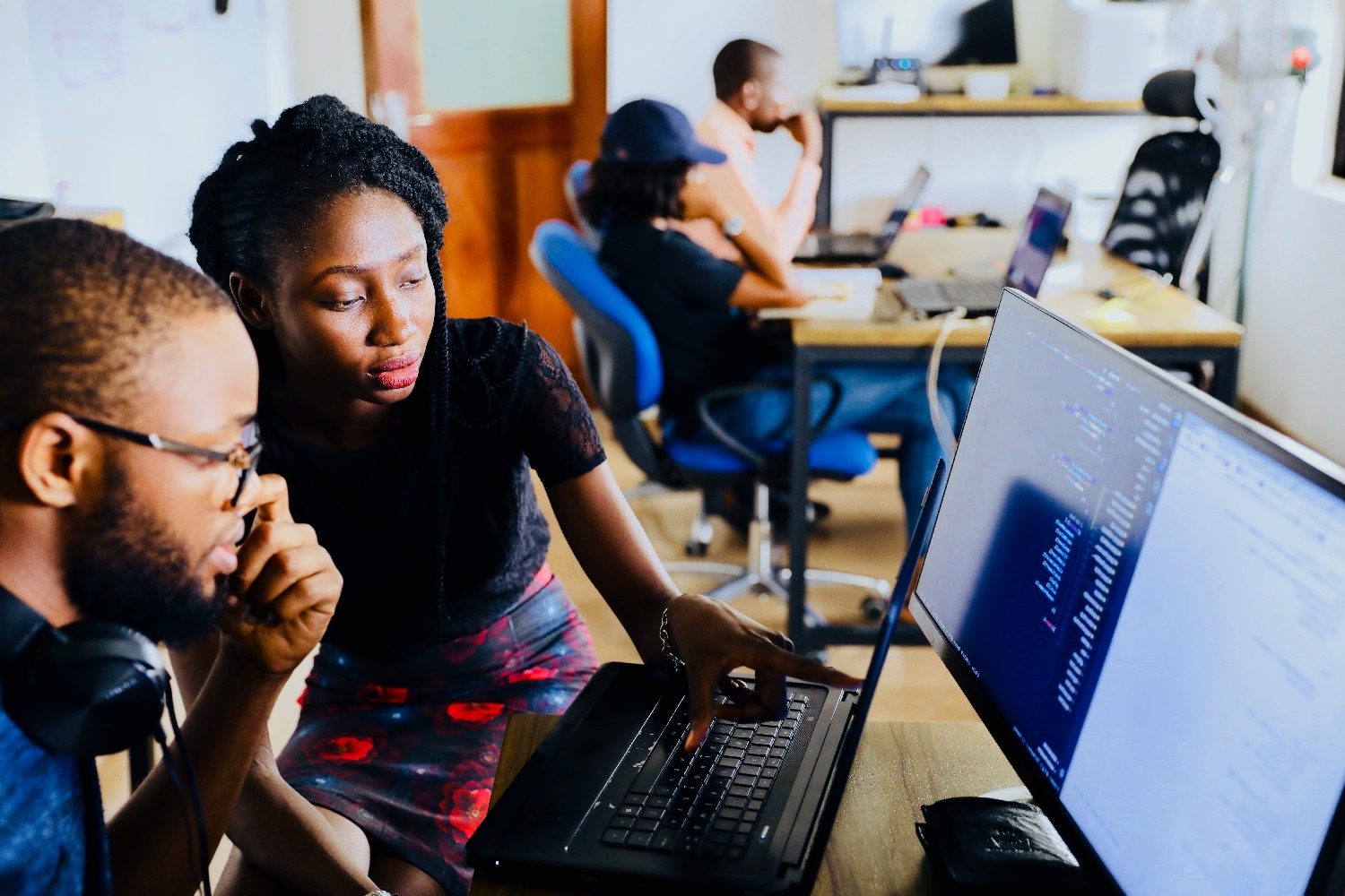 Person pointing out something on monitor to colleague