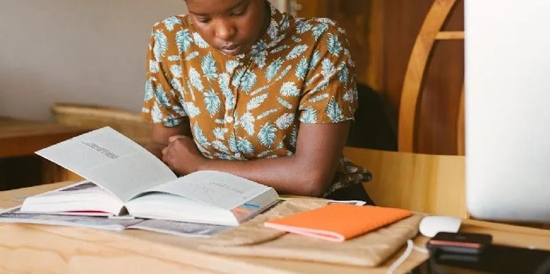 Woman sitting at desk, reading a book