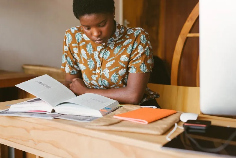 Woman sitting at desk, reading a book