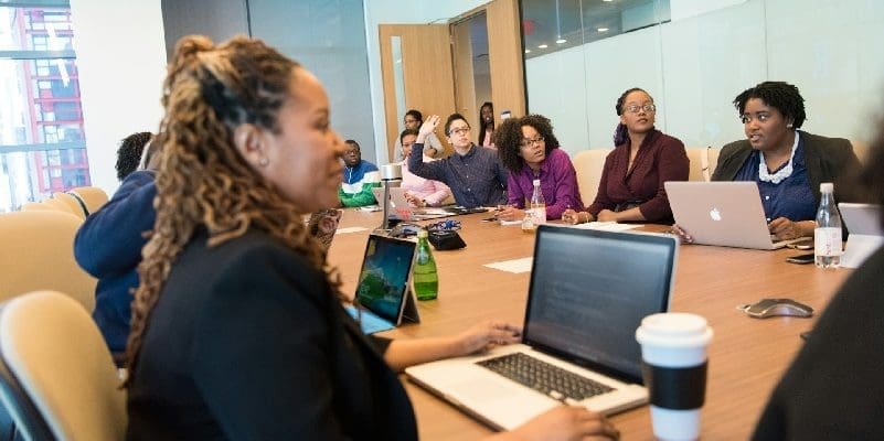 Staff members sitting around table, using laptops