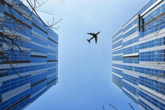 an airplane fly over high rise buildings