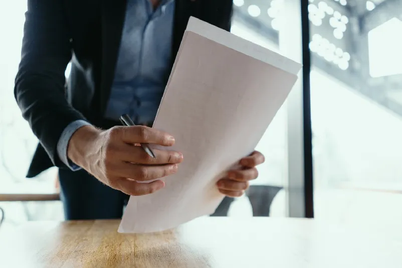 Lawyer picking up stack of papers, while holding pen