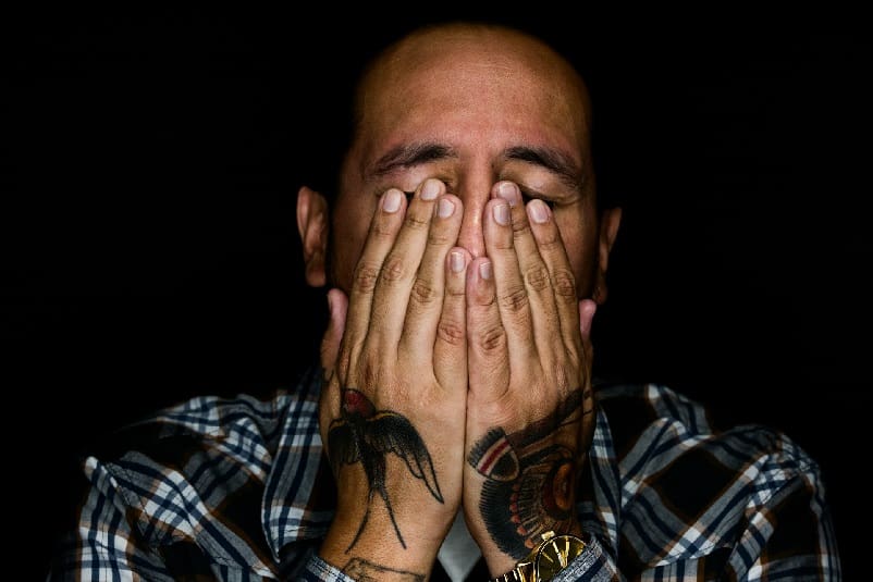 Man clasping his hands to his face