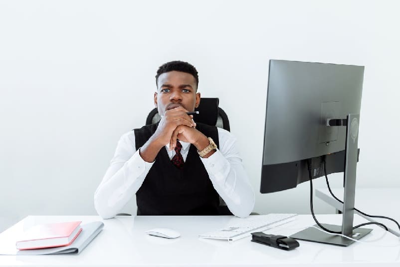 Man sitting at desk with computer and notebook