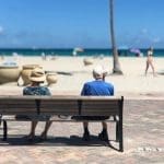 Elderly, retired couple sitting on a bench at the beach