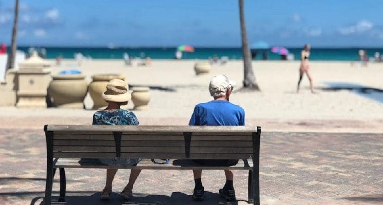 Elderly, retired couple sitting on a bench at the beach